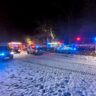 Na sněhem pokryté cestě a přilehlé louce stojí několik vozidel hasičů, záchranné služby i policie s rozsvícenými výstražnými světly, která barví okolí do modrých a červených odstínů / Foto: HZSKHK